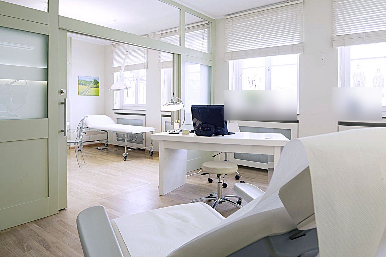 Sprechzimmer mit angrenzendem Untersuchungsraum hinter Glastrennwand