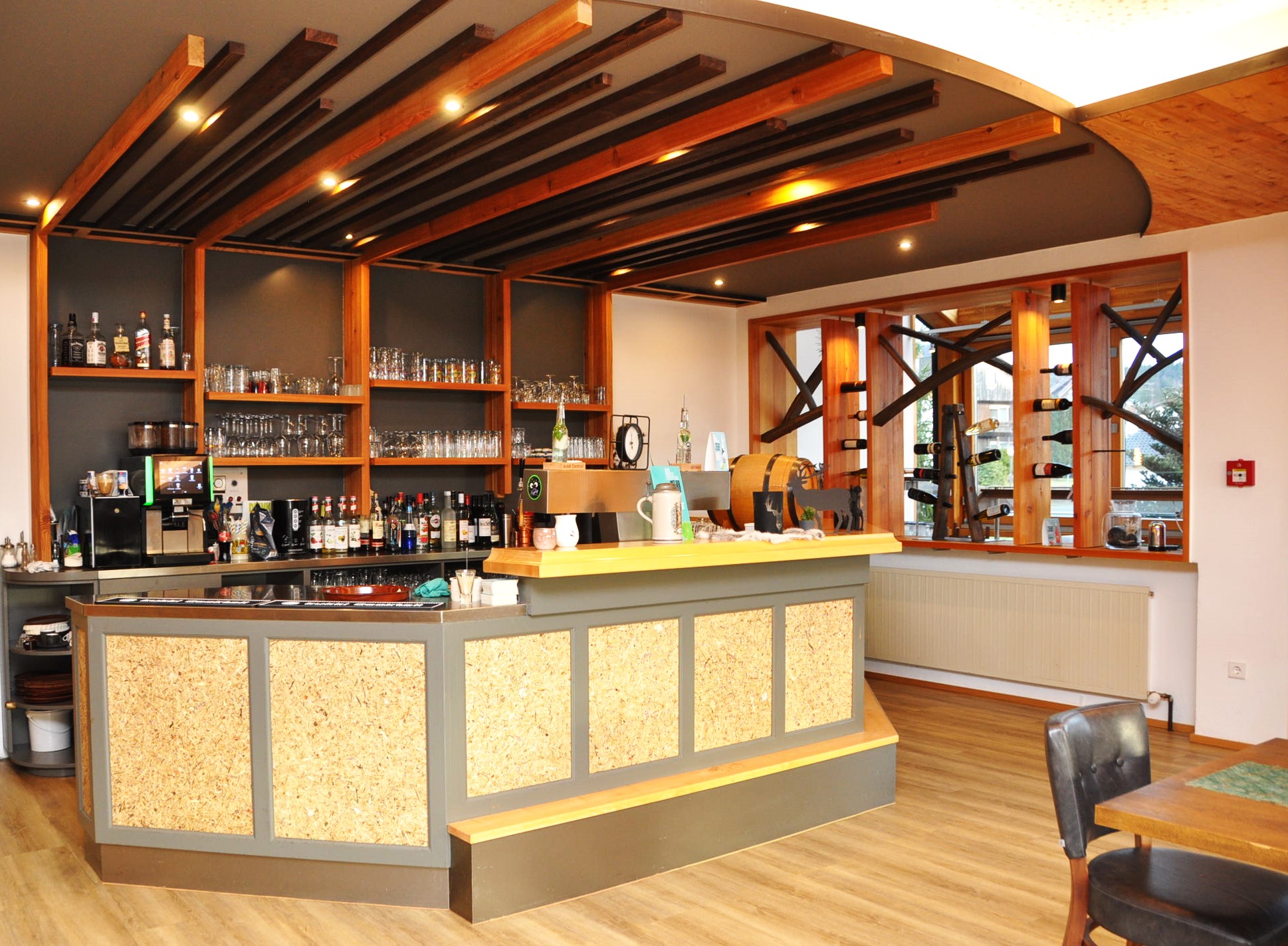 Hotel bar with wooden ceiling, wine rack, and coffee machine