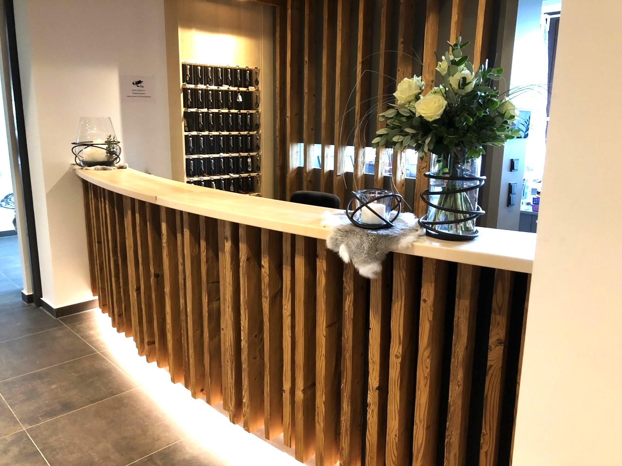 Hotel Hubertus reception — curved reclaimed wood counter with indirect lighting